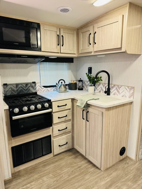 The kitchen with microwave, stove top, stove fan, oven, and sink. 