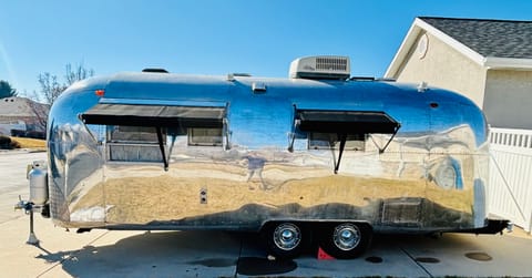 Driver side view showing tandem axels, extended awnings, tongue & hitch, rooftop heating/air conditioning unit, vents, etc. Body is clean of any dents or other damage. Very shiny! Everything you want in an Airstream! 