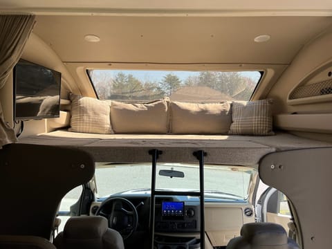 Over-cab queen bunk features power window shade and TV.