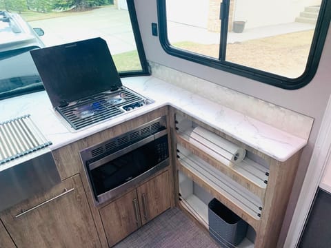 Two burner stove, microwave, large sink with cover so sink can be used as counter space.