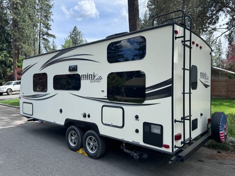 Driver side exterior with access to fresh water hookup, shore power hookup, and water tank heater access.