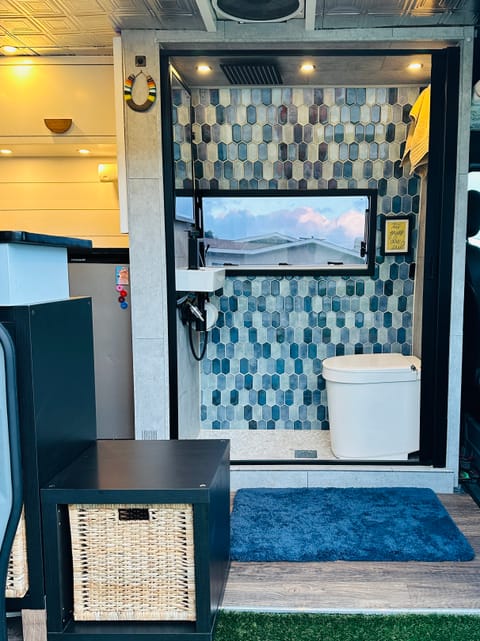 Rain and wand shower in this spacious bathroom complete with bagged composting toilet, sink, mirrored medicine cabinet, shower supplies, a sliding door closure and window to gaze through. 