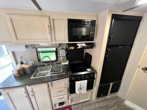 Kitchen includes many stocked essentials, a 3 burner gas stove, an oven, a microwave, a fridge/freezer, and a double sink. 