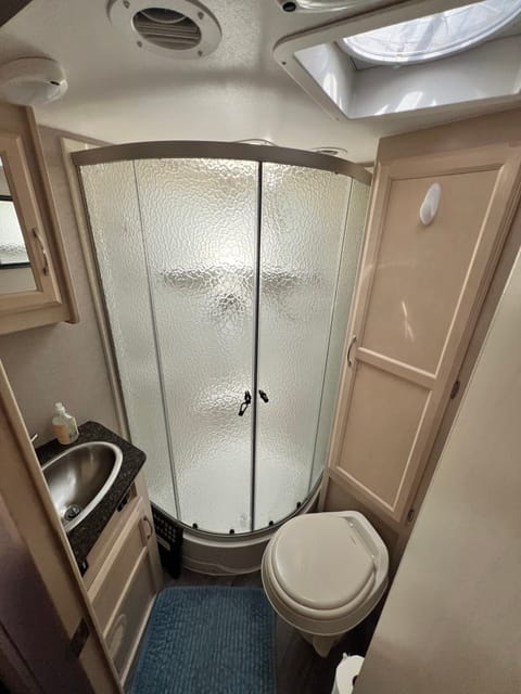 Bathroom includes a shower, sink, toilet and a Maxxair exhaust fan. 