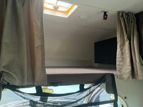 Above cab loft. Our teenager's "room" when she is with us. Curtains = a little extra privacy.  The TV has an extendable arm and can be swung out for the rest of the cabin's use.