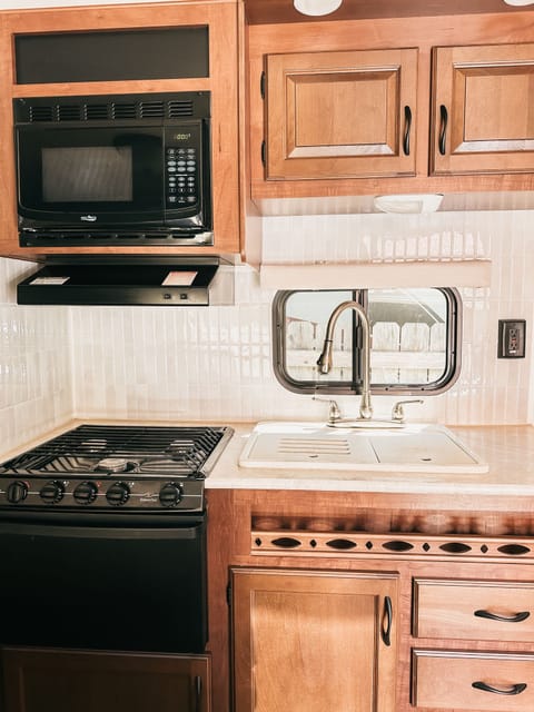 The propane stove has 3 burners with a beautiful backsplash for easy clean up, a microwave above, & oven below.