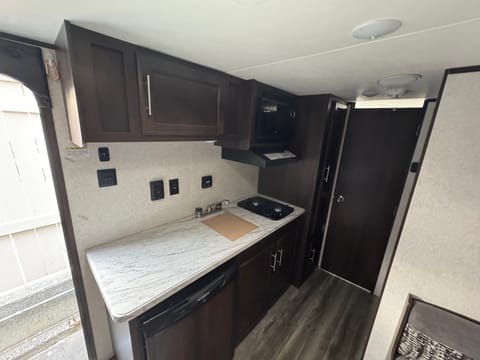 Microwave, 2 burner propane stove, sink (has cover on it) and fridge