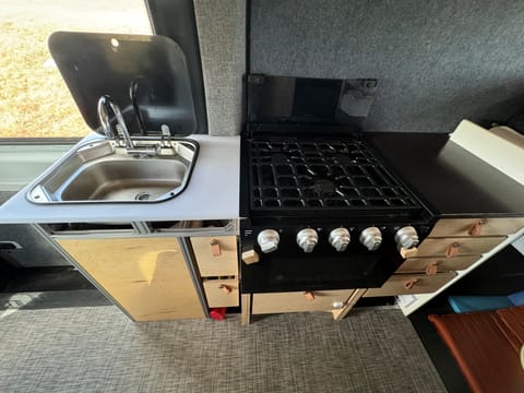 Dining area features gas stove with oven, sink with folding faucet and plenty of storage.
