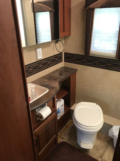 Quiet large bathroom for an RV this size. There is actually enough room to change or dry off after a shower. Two large vanity mirrors with storage behind them.