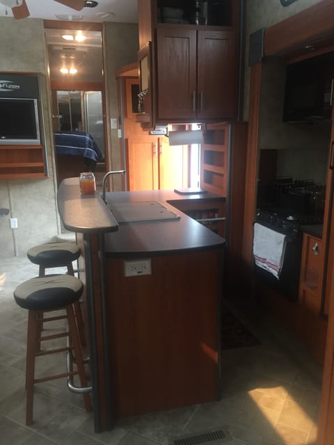 bar and kitchen complete with 3 burner stove, oven, microwave, double sink, and refrigerator and plenty of space and fully stocked with cooking utensils and spices.