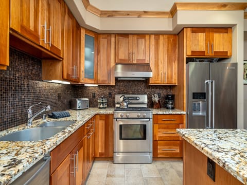 Well lit cooking area all granite counter tops and tile flooring throughout.