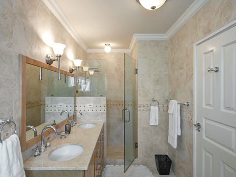 The lovely en-suite master bathroom features a stand-alone shower, tub, and his & hers sinks