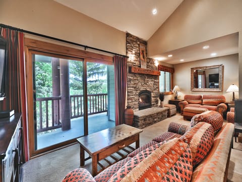 Living room features a beautiful rock gas fireplace and access to the private patio
