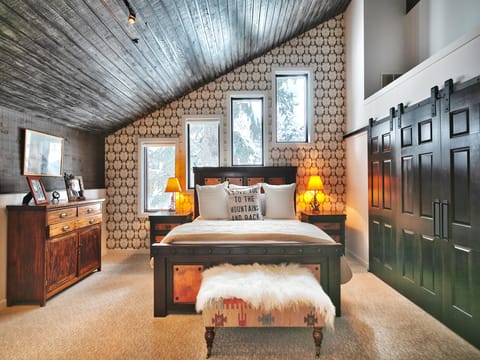 Wood and bronze bedframe in the main bedroom, designer wallpaper and barn door style closets