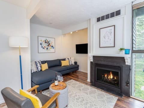 The cozy living room features a gas fireplace, flat screen tv, dining area and access to the deck and kitchen.