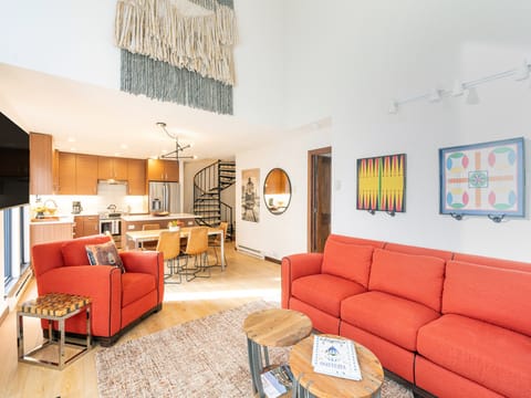 Open and spacious living room with high ceilings that is adjacent to the kitchen for family gatherings while cooking and lounging.