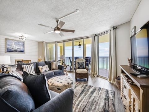 Spacious living room with plenty of seating and large flat screen TV, beautiful view of the Gulf with balcony access