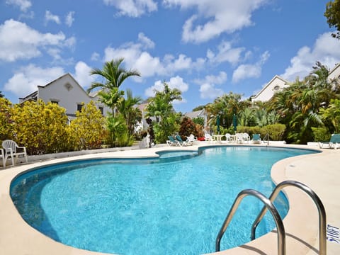 The large community pool with sun loungers, umbrellas, chairs, and a pool shower