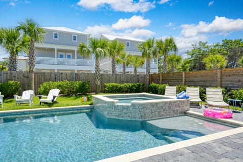 Lush backyard pool and hot tub area with loungers.