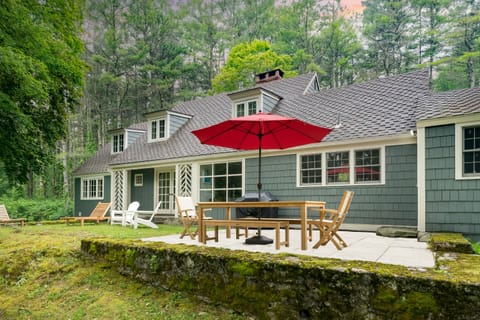 Spacious deck features an outdoor dining table and seating that looks toward the trees.