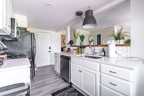 our contemporary kitchen adorned with pristine white cabinets, offering a sleek and modern aesthetic. Equipped with essential elements including a sink, stove, oven, and various kitchen appliances, our space is designed for both functionality and sty