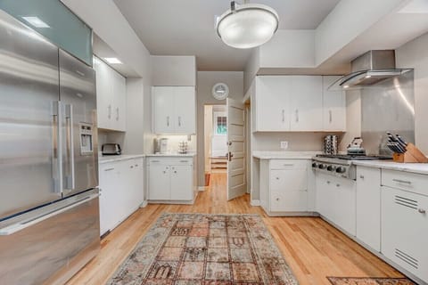 An Expansive Kitchen Bathed in Inviting Light, Featuring a Large Fridge, Toaster, Stove, Coffee Maker, and a Generous Array of Essential Utensils