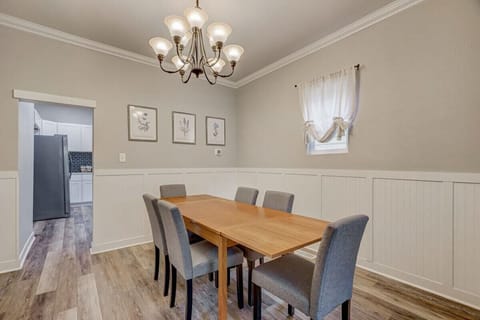 Gather around a Stunning Table with a Beautiful Chandelier, Enjoy Soft Natural Lighting from the Window, and Appreciate the Proximity to the Kitchen for Added Convenience