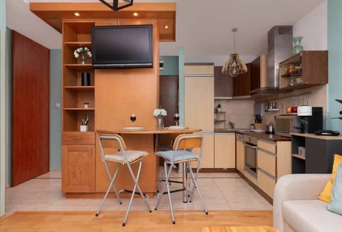 A transitional view between the kitchen and living area, with a small dining table and chairs, and additional storage in wooden cupboards.

