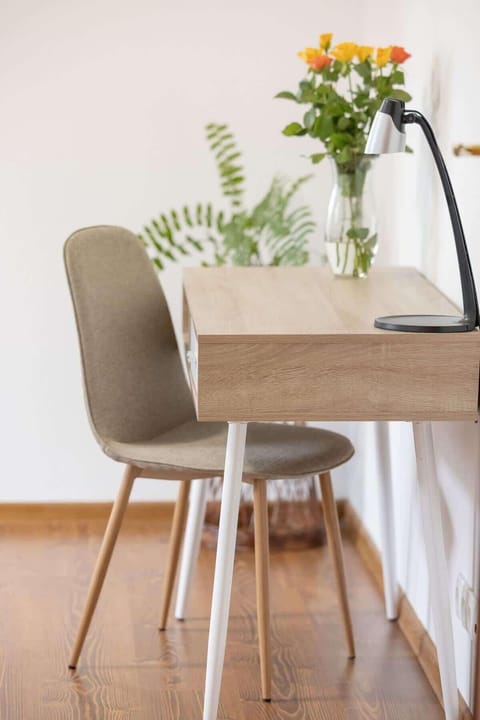 A bedroom with a grey bedspread, wooden floors, and a small table and chair, creating a comfortable and inviting sleeping area.

