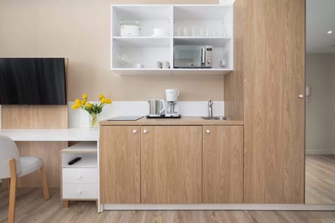 A functional kitchen area with open shelves, kettle, and a clean, minimalist design.

