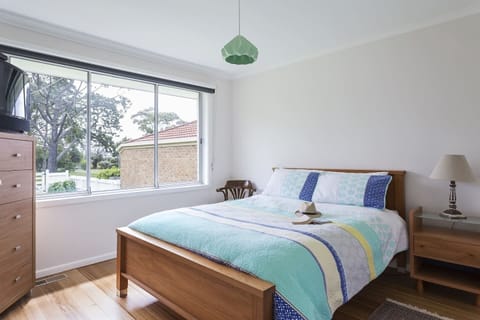 The primary bedroom is set with a queen bed under a retro pendant light and offers access to an ensuite. There's ample space to fold and store your clothes in the dresser. 