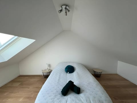 "This room is bathed in natural light thanks to a well placed Velux. The floor is covered with wooden floors, offering warmth and elegance. White walls enhance the brightness of the room. Next to the bed is a bedside lamp for a soft atmosphere, as well as a practical coffee table for laying personal items. The whole creates a serene and comfortable room, ideal for relaxing and enjoying the natural light."