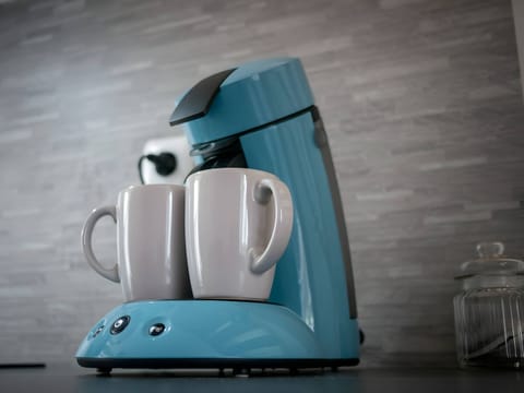 "Blue coffee maker with these mugs in the kitchen "
