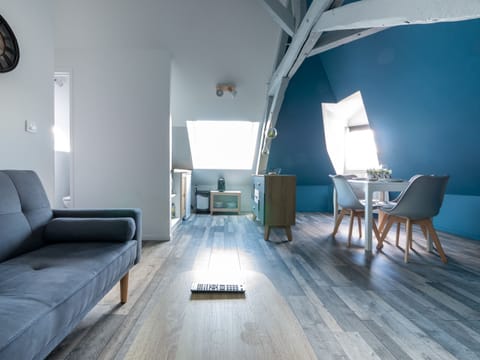 "This open kitchen is bathed in natural light thanks to a well-placed window. The white and blue walls create a bright atmosphere. The kitchen is functionally equipped, with a comfortable seating area nearby. The dining room is also integrated into this room, promoting conviviality during meals. This space combines functionality, brightness and style."