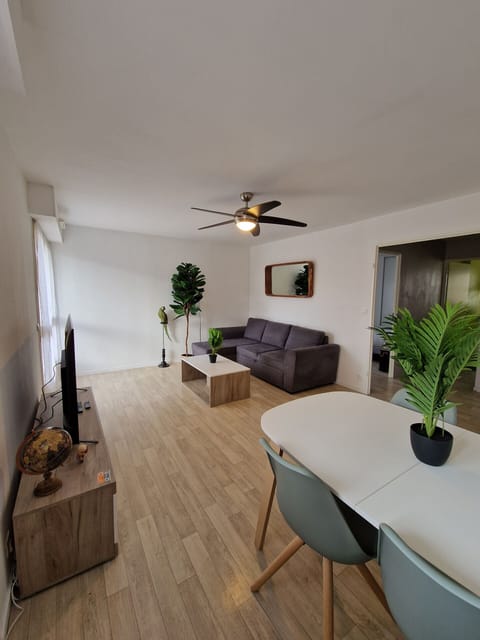 "Discover the living room of the Le Square apartment in Le Mans through this photo. You can see the dining table, TV cabinet, TV screen, sofa, coffee table and green plants. Enjoy a friendly, comfortable space for relaxing and entertaining."