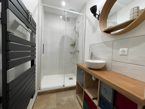 Modern bathroom with walk-in shower, elegant basin and illuminated mirror.