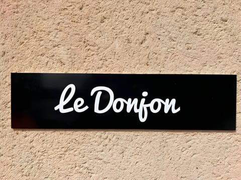 "Discover the elegant wall plaque in the "Le Donjon" apartment. A black plaque with the white inscription "Le Donjon" adding a touch of elegance and authenticity to the apartment's entrance."