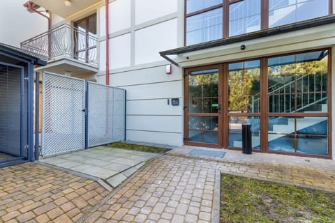 The entrance of a modern building with glass panels and a paved walkway leading to the main door.
