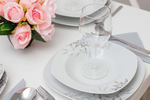 A close-up of an elegant table setting with white plates, crystal glasses, and a pink floral centerpiece.

