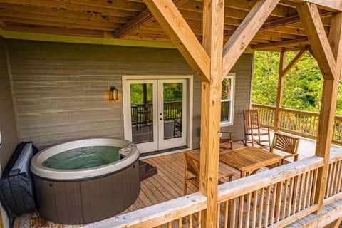 Covered deck featuring a private hot tub with mountain and lake views for a relaxing retreat.