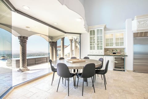 Modern dining area with a round table, sliding doors, and pool view.