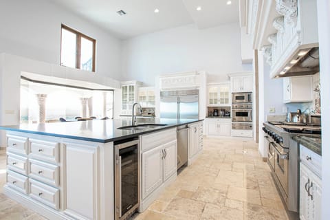Spacious kitchen with vaulted ceiling, dark island, and stainless steel.