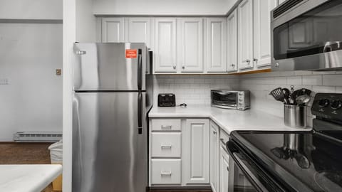 Kitchen: Well-equipped kitchen, stainless steel appliances, white counter and cabinets, range of basic cookware
