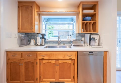 Warm wooden cabinets, blue tiled backsplash, and well-organized shelves, complete with a window above the sink to let in natural light.