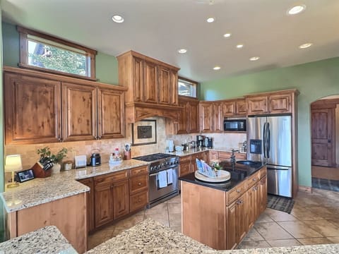 Gourmet Haven: A fully equipped kitchen boasts custom cabinetry, stainless appliances, granite countertops, an island, and a bar top, ready for culinary adventures.