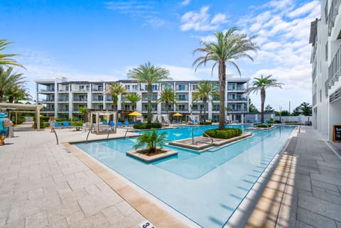 Modern resort-style pool area with palm trees and contemporary buildings.