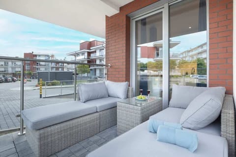 A spacious balcony with wicker furniture and cushions, offering a relaxing outdoor seating area.


