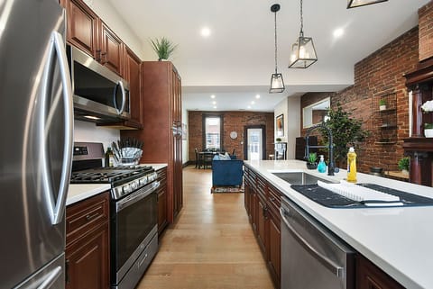 Modern kitchen with brick walls, brown cabinets & reliable appliances.