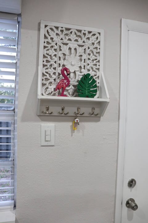 A decorative wall shelf with hooks and tropical accents.