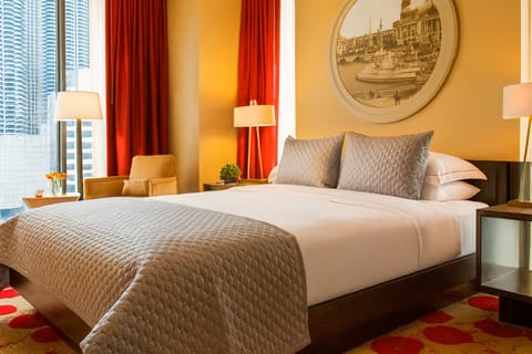 Unwind in crisp linens beside glowing city-lit windows.
